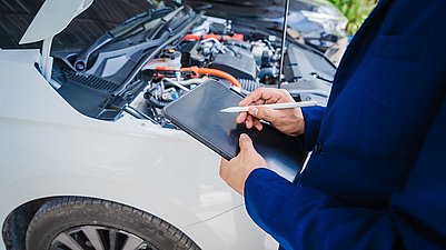 Ein Mann kontrolliert den Automotor mit einem Ipad