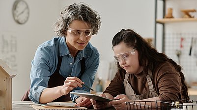 Frau erklärt Mitarbeiterin ein Programm. 