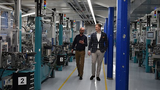 Zwei Männer laufen durch Fabrikhalle