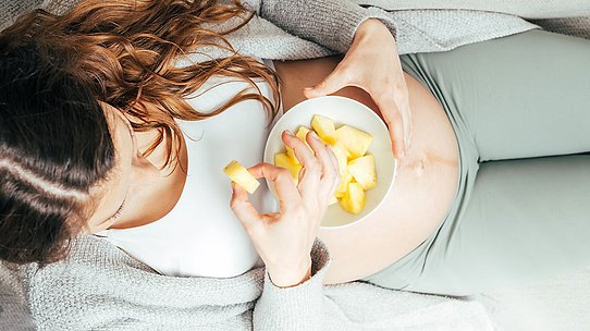 Schwangere Frau isst Früchte.